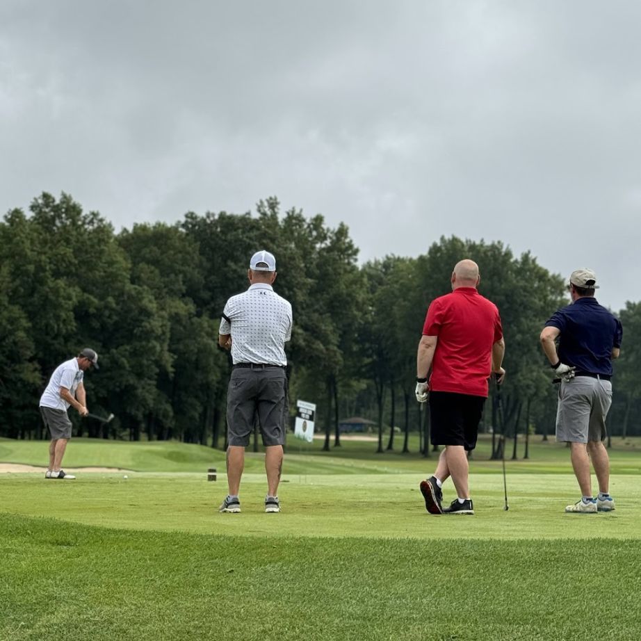 men watching golfer swing