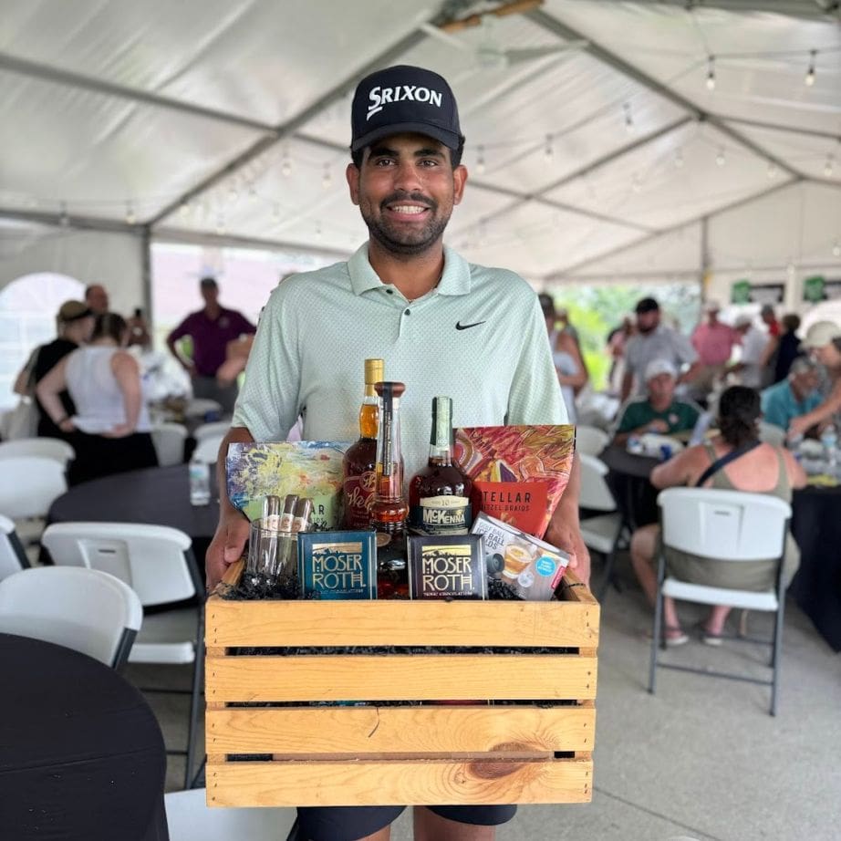 man holding raffle prizes at Golf Scramble dinner